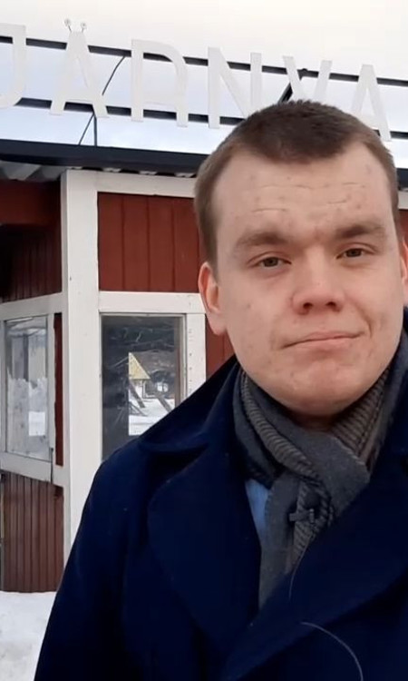 Socialsekreterare Oskar Konradsson står utomhus med blå jacka och grå halsduk. Han står utanför ingången till Tjärnvallen. 