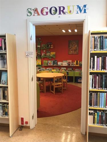 Bilden visar Sagorummet på biblioteket i Vilhelmina. Bilden föreställer en dörröppning in till sagorummet och ovanför dörröppningen finns en skylt i färgglada bokstäver där det står "Sagorum"