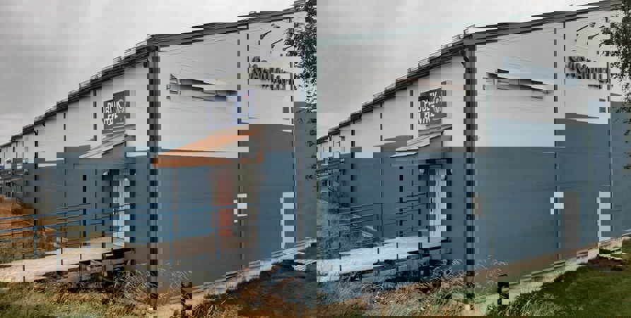 Bilden visar ishallen utifrån. Hallen är blå nertill och vit upptill. Man ser skylten "Sagahallen" på kortsidan och på långsidan finns en ramp till en dörr med texten "Publik Entre" och VIK:s logga.