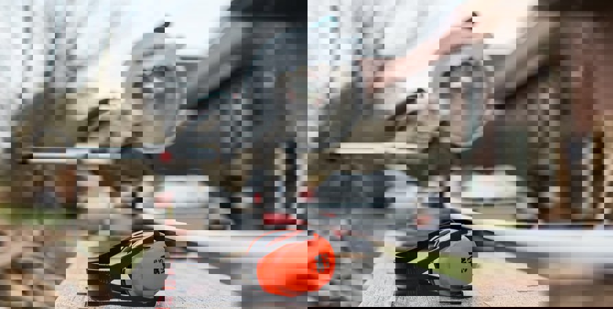 Ett foto där hörselkåpor som ligger på en bänk är skarpt i fokus och suddigt i bakgrunden syns fasaden på ett låghus.