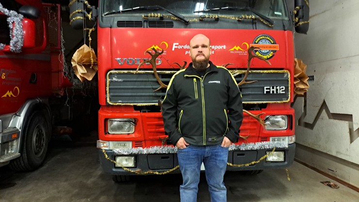 Mikael Hamberg står fram en fronten på en röd lastbil som tillhör Fordons- och transportprogrammet.
