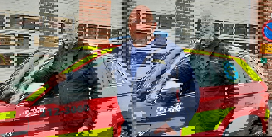 Magnus står framför en av räddningstjänsten bilar.